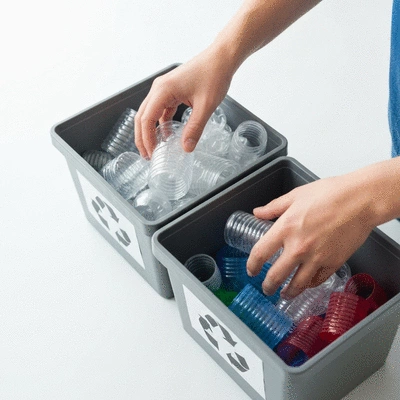 Close-up of hands sorting different types of plastic waste into recycling bins, promoting community engagement